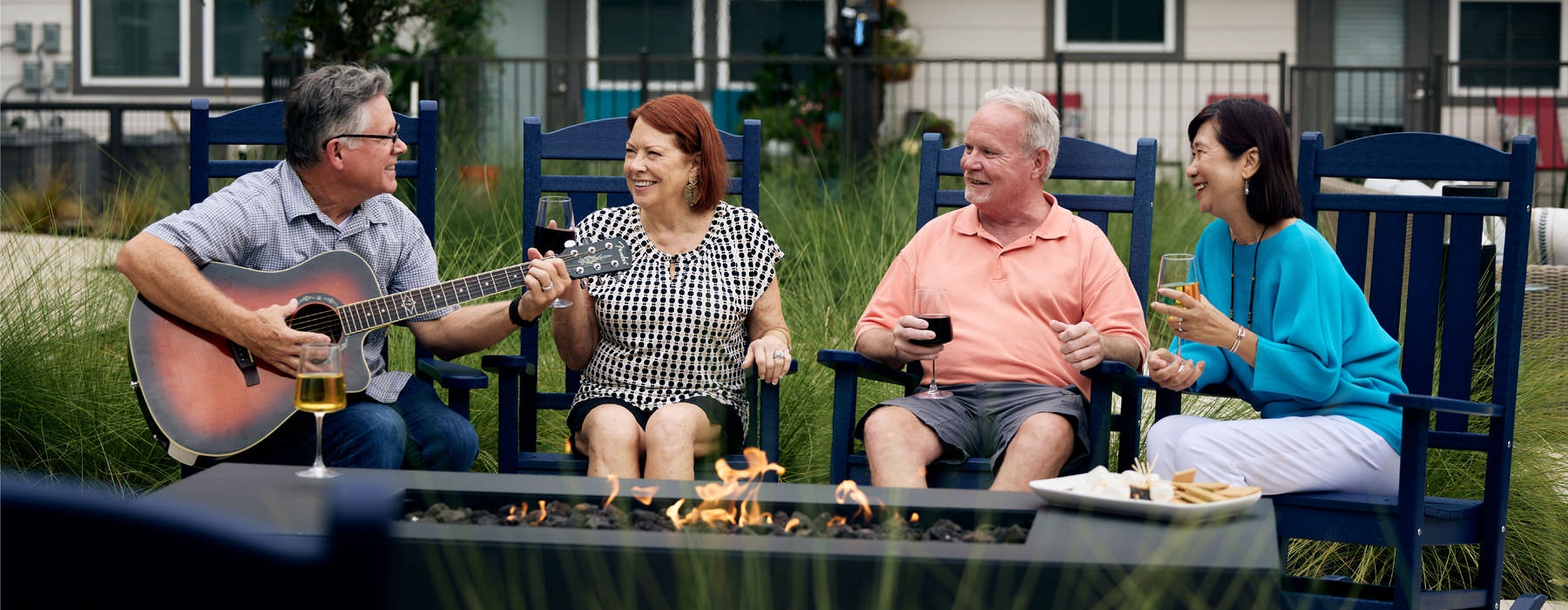 people sitting around fire and a man playing a guitar